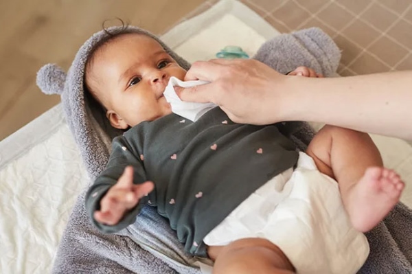 Sử dụng khăn khô để lau miệng, lau dãi cho bé